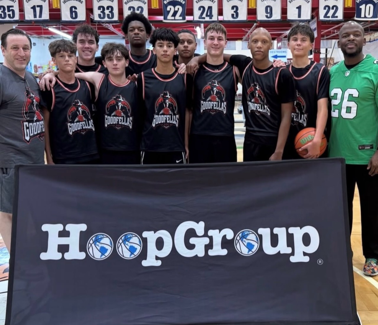 Goodfellas players and coaches posing with a Hoop Group banner